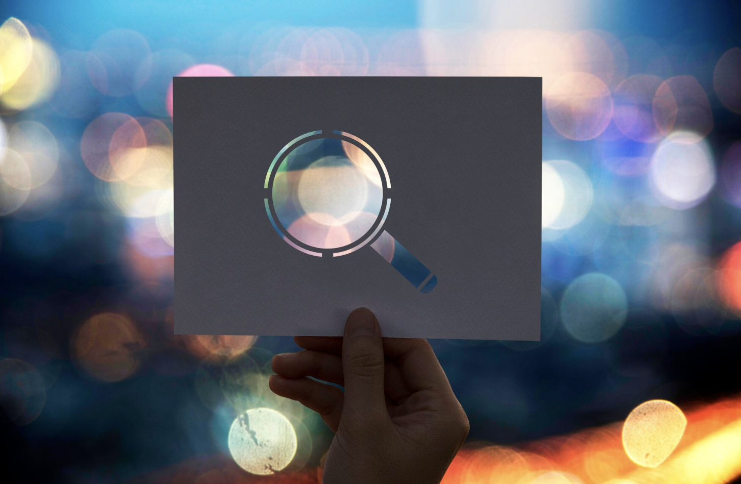 paper magnifying glass in front of some blurry street lights